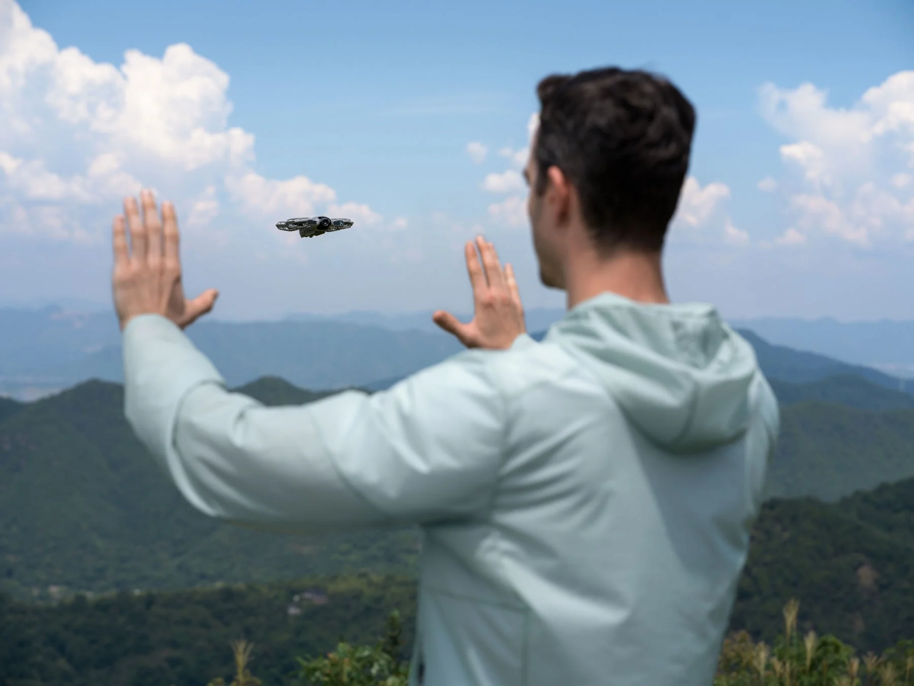 ドローンに両手でジェスチャー操作し距離を調整する男性