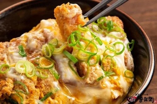 箸で持ち上げられた玉子とじかつ丼のクローズアップ