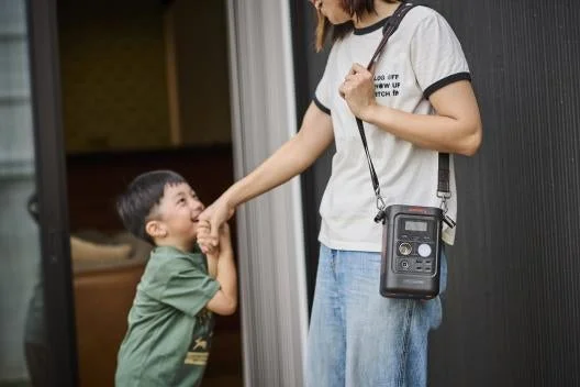 Jackeryポータブル電源300Dを肩掛けして持ち運ぶ女性と子供