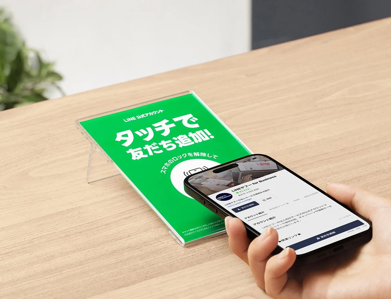 スタンドタイプのNFCタグにスマートフォンをかざしてLINE公式アカウントを友だち追加する様子。