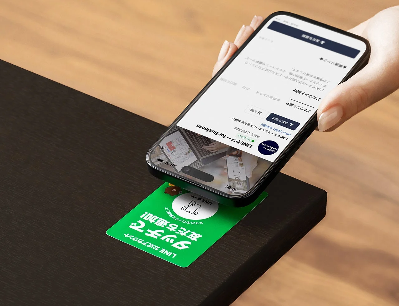 ステッカータイプのNFCタグにスマートフォンをかざしてLINE公式アカウントを起動する様子。