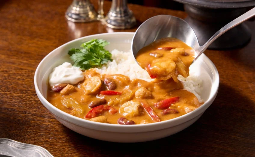 ご飯に盛り付けられたオマール海老ソースと帆立のケイジャン風フリカッセ
