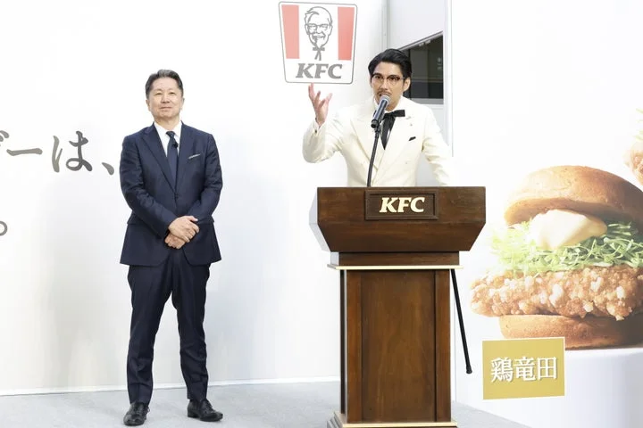 遠藤社長が「ケンタの鶏竜田バーガー」への自信を語る隣で賀来賢人さんが見守る