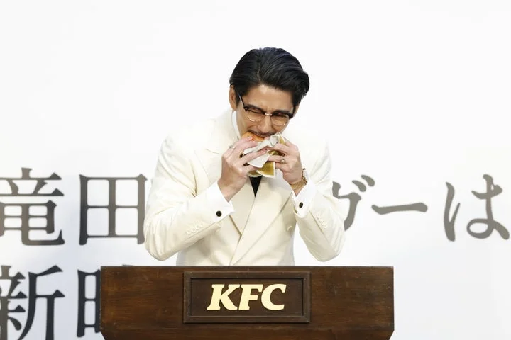 賀来賢人さんが「ケンタの鶏竜田バーガー」を一口試食する様子