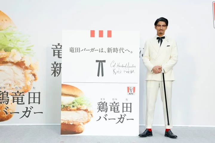 カーネル・サンダース姿の賀来賢人さんが「竜田バーガーは、新時代へ。」パネルの前で立つ