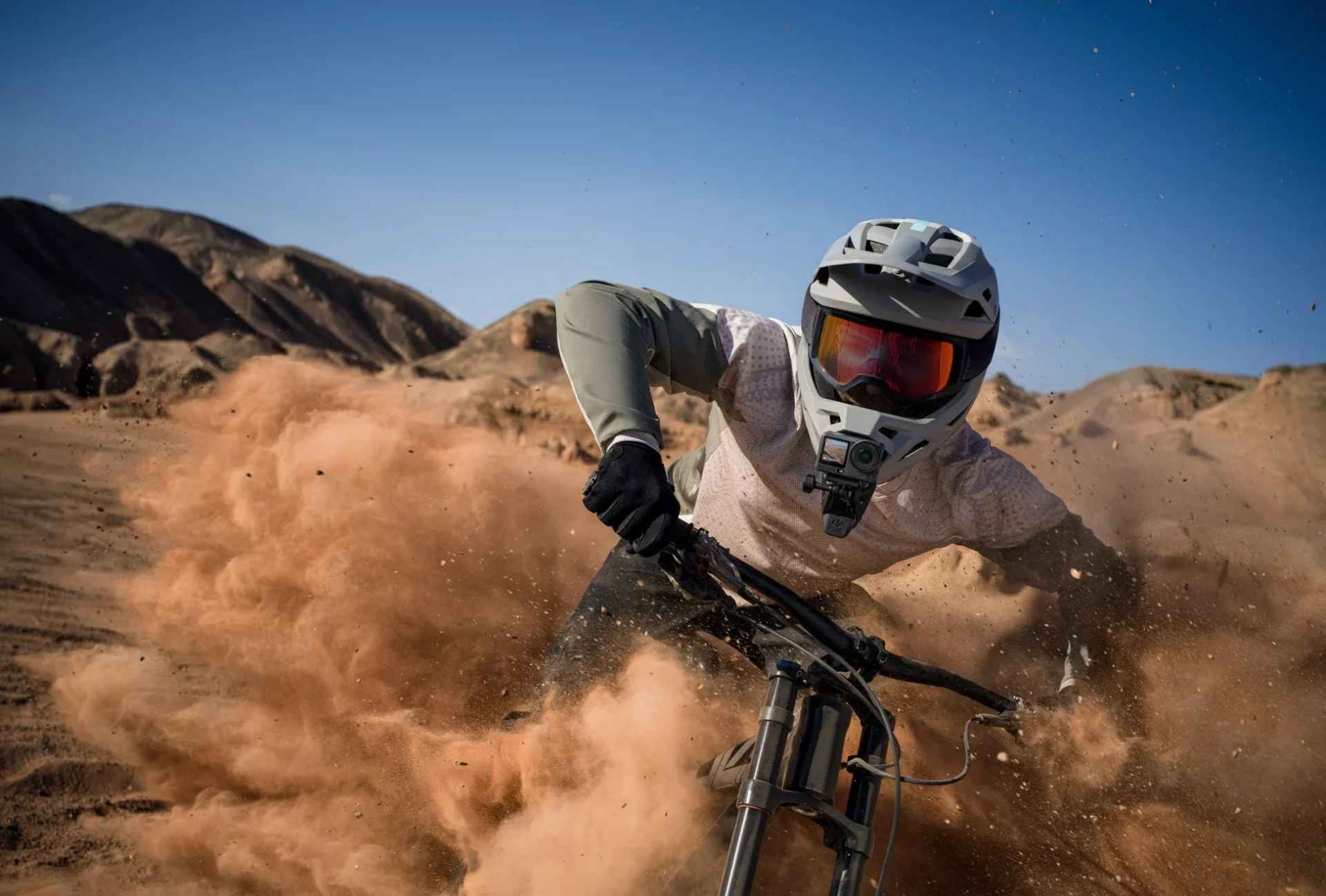 マウンテンバイクで砂塵を巻き上げながら走行するライダー、胸にOsmo Action 6を装着