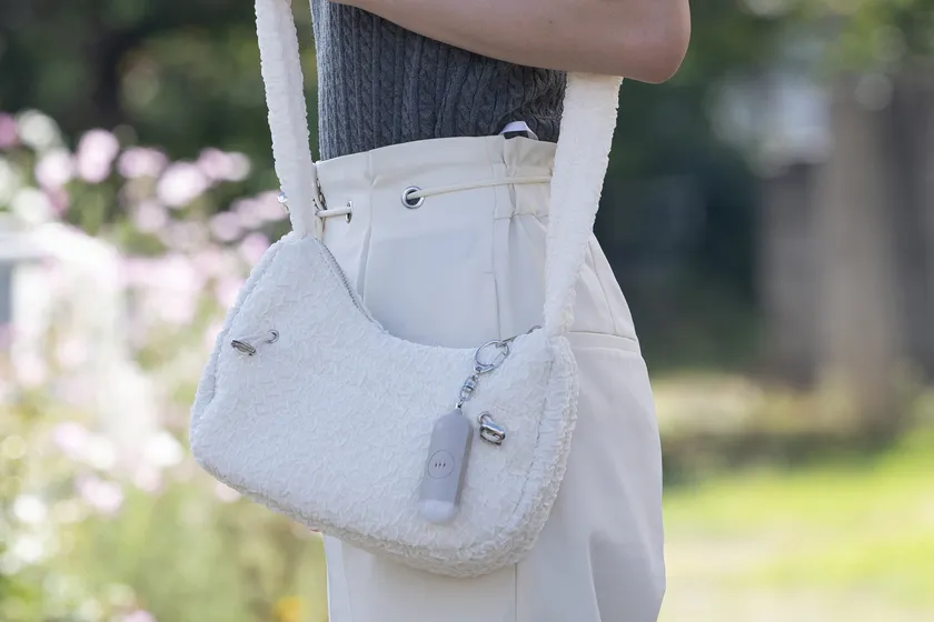 バッグに防犯ブザーを付けて外出する女性