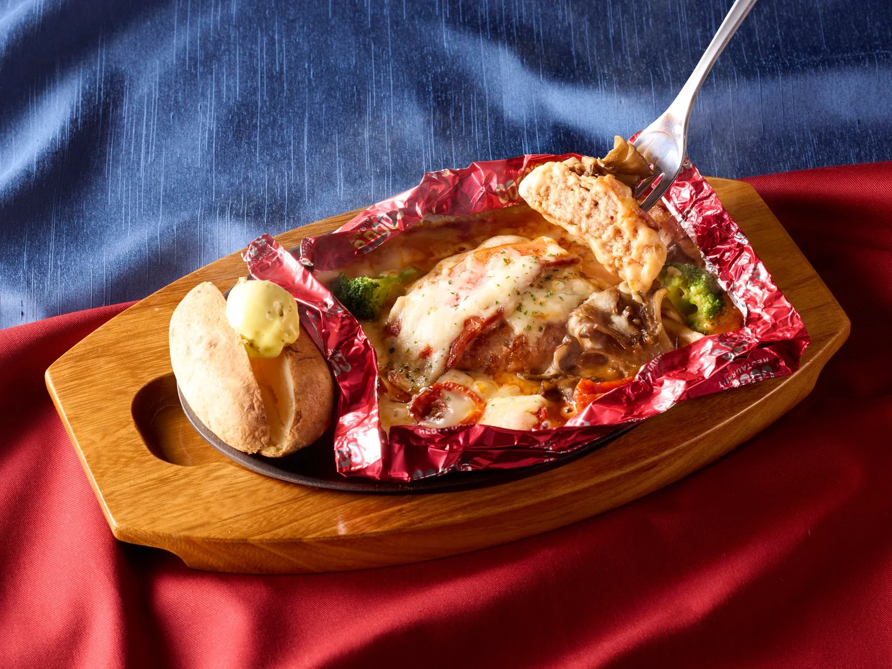 燻製ベーコンと舞茸の包み焼きハンバーグをフォークですくい上げる様子