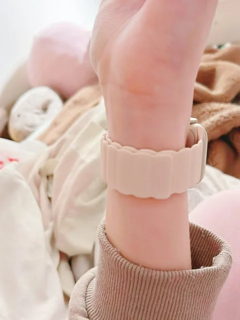 淡いピンクのシリコンバンドを着用した手元