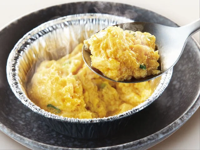 ホイルでぐつぐつ煮込んだチーズケランチムをスプーンで取り分ける様子