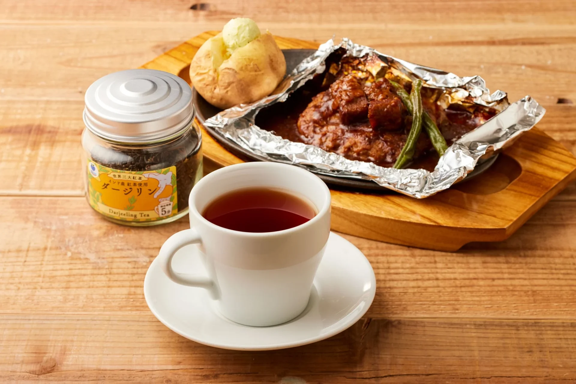 ダージリンの紅茶と濃厚ビーフシチューの包み焼きハンバーグが木製テーブルに置かれている