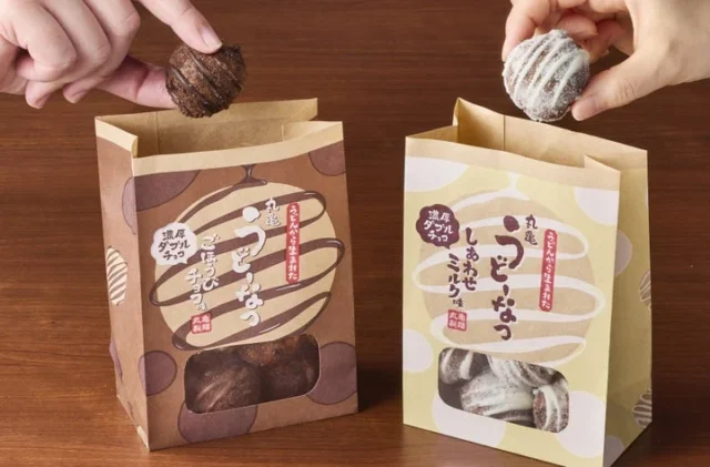 丸亀うどーなつ濃厚ダブルチョコ ごほうびチョコ味としあわせミルク味のパッケージを手に持つ様子