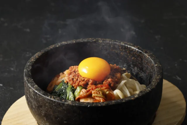 熱々の石焼ビビンパに卵黄が乗った様子