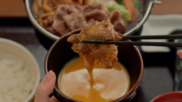 石原さとみさんが牛すき鍋の牛肉を溶き卵にくぐらせる