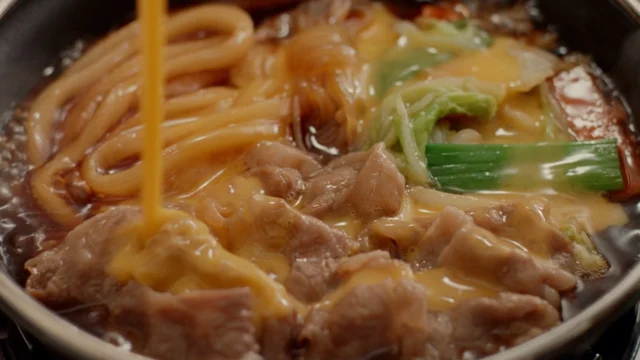 牛すき鍋に溶き卵を回し入れ、卵とじにする様子