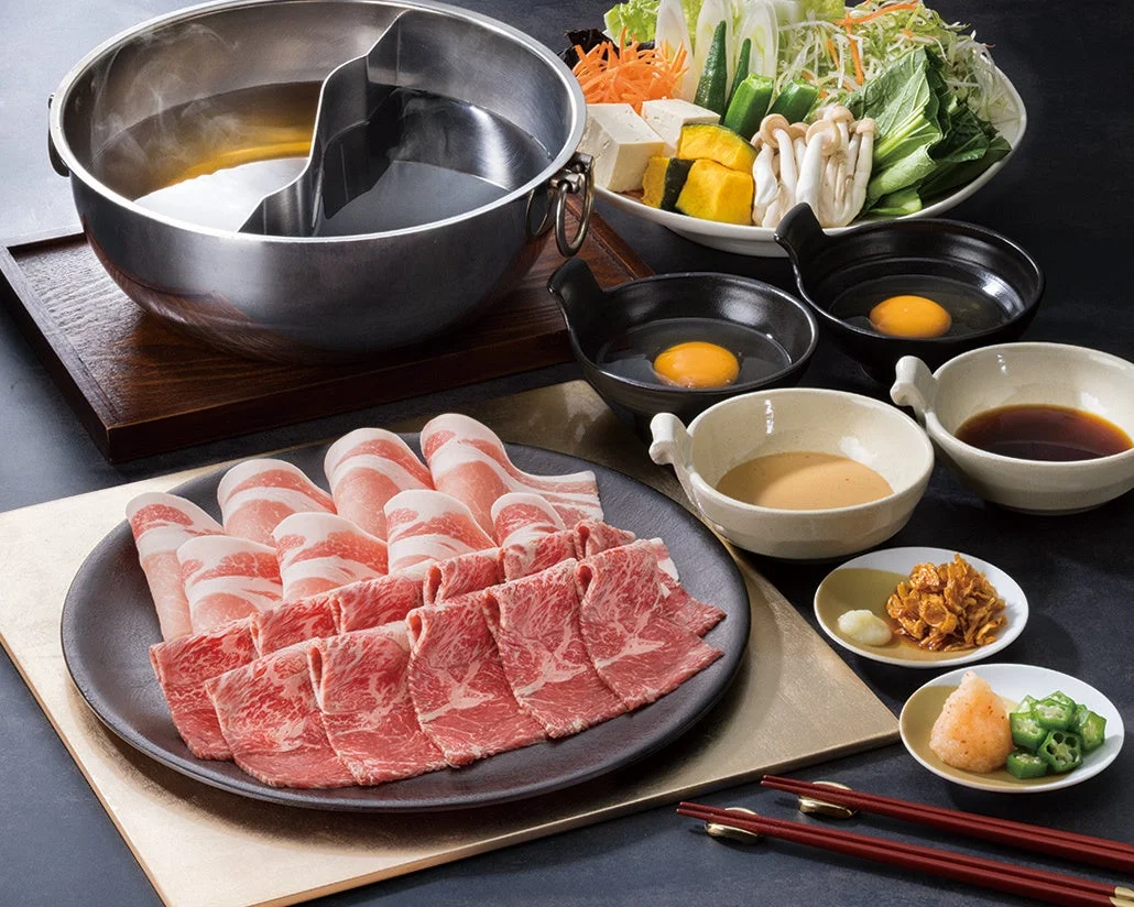 しゃぶ葉の黒毛和牛と九州黒豚、野菜、たれが並んだ豪華なテーブルセット