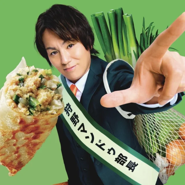 狩野マンドゥ部長がマンドゥと食材を持ち、指をさすポーズ。