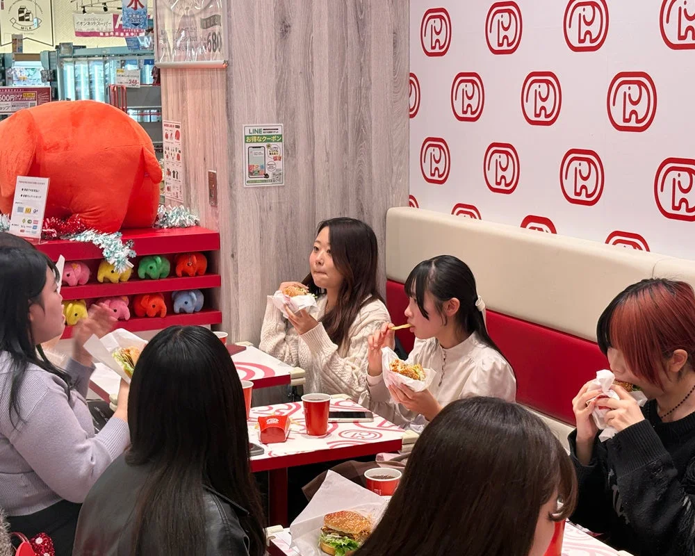 ドムドムハンバーガーの新メニューを試食し感想を話し合う学生たち