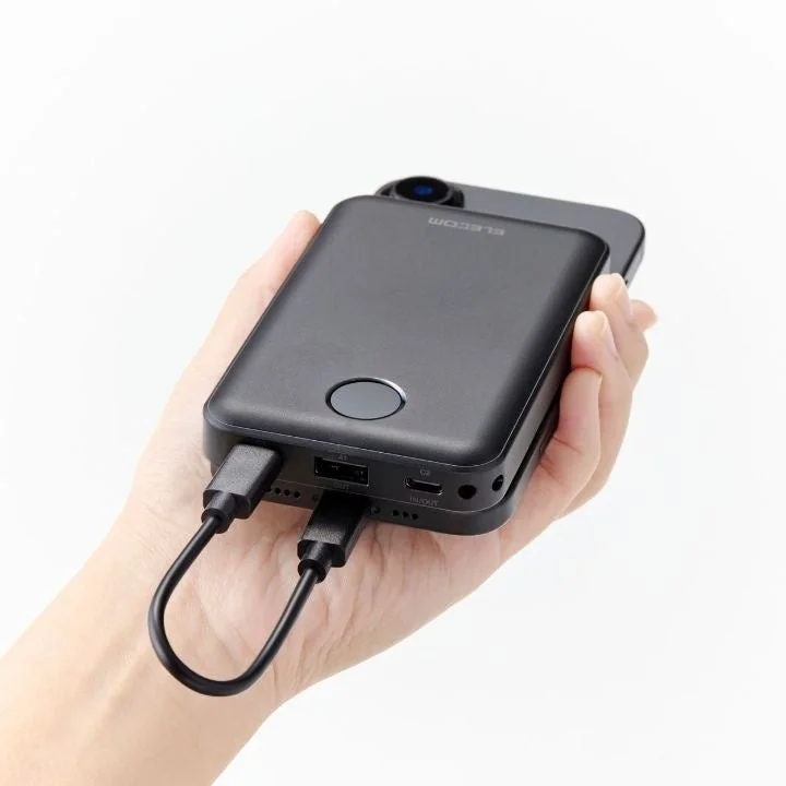 手に持たれたブラックのモバイルバッテリーと接続されたスマートフォン