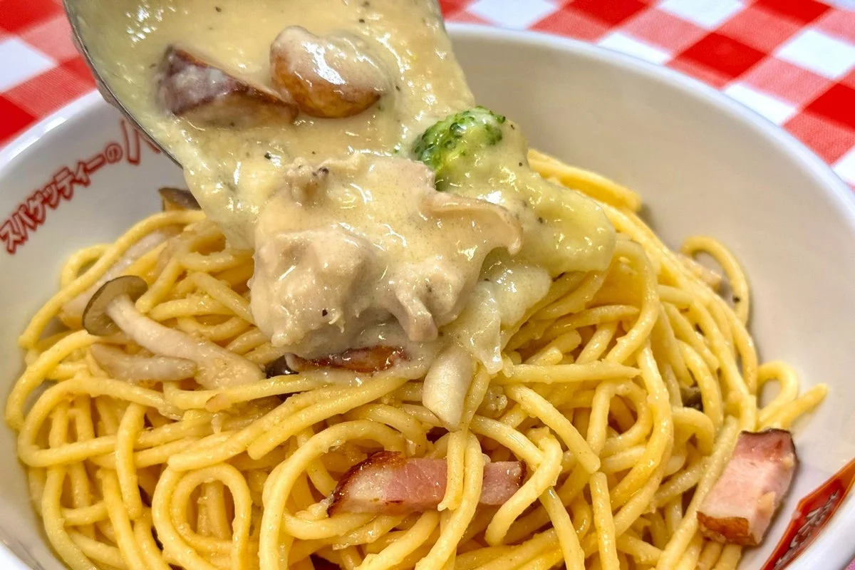 極太麺のスパゲッティーにシュクメルリ風シチューをかける様子