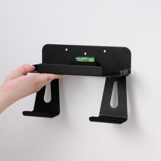 壁掛けスタンドを壁に設置し水平器で位置を確認する様子