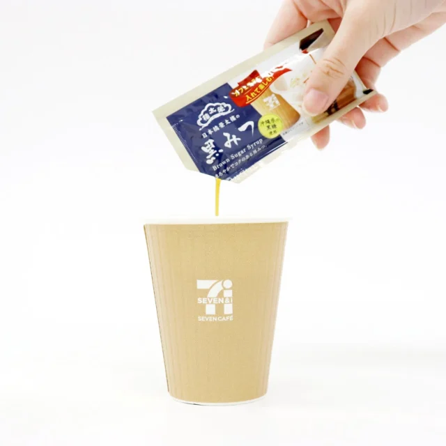 セブンカフェのホットカフェラテに黒みつを入れる様子