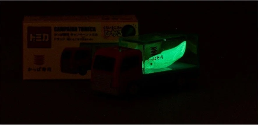 かっぱ寿司限定トミカ トラック（暗いところで光るいか）が暗闇で光る様子
