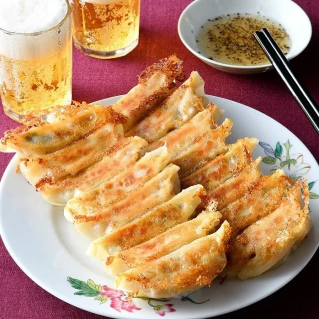 白い皿に盛り付けられた赤坂珉珉の焼き餃子と酢コショウのタレ