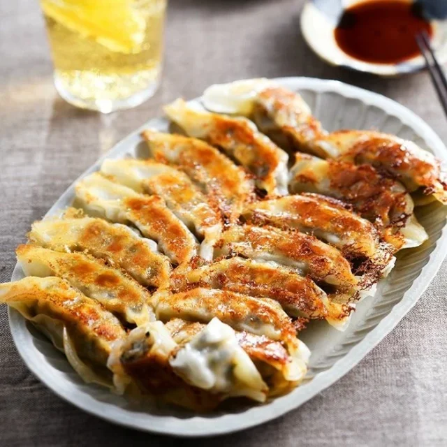 白い皿に並べられたハマヤの鰹タタキの龍馬ギョーザとハイボール