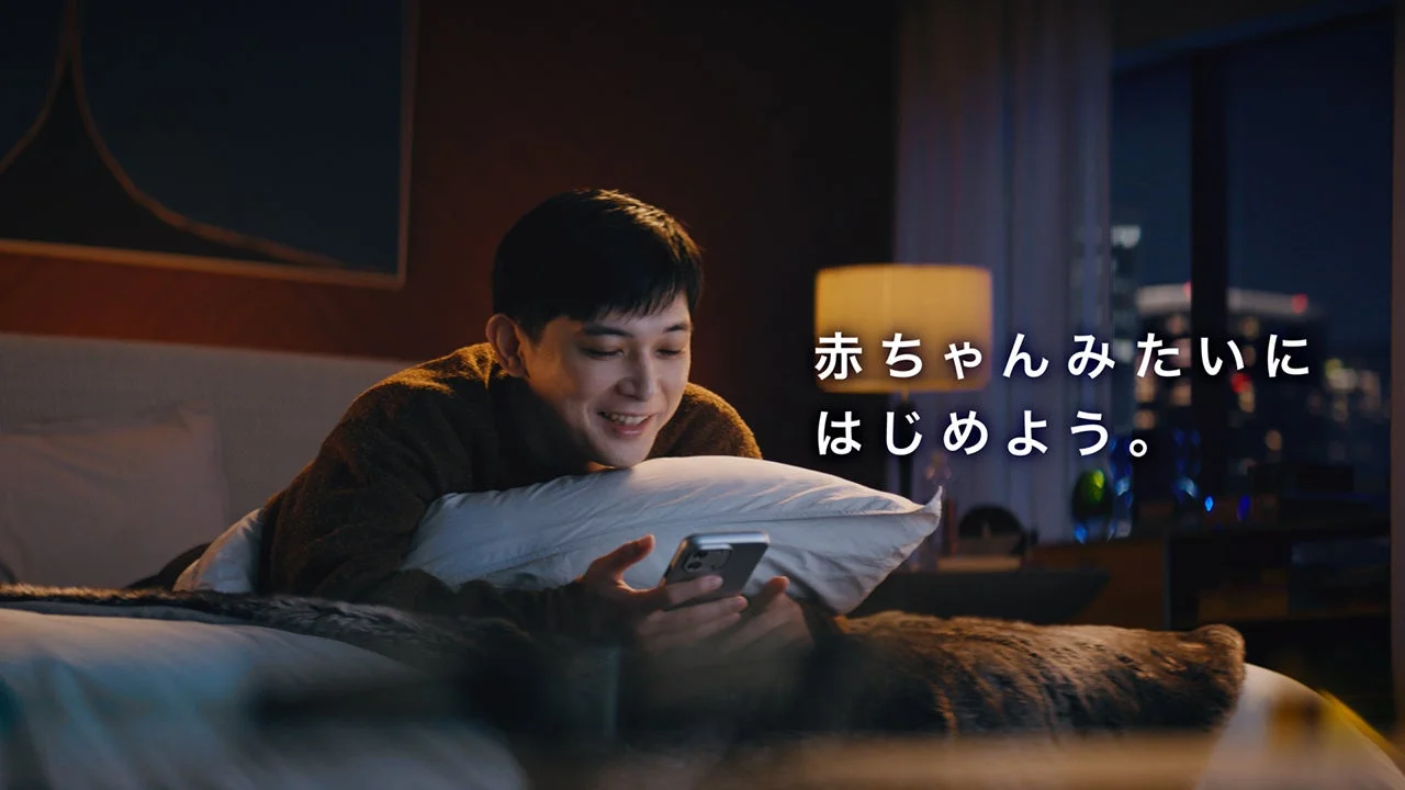 吉沢亮さんがベッドでスマホを操作し「赤ちゃんみたいにはじめよう。」の文字