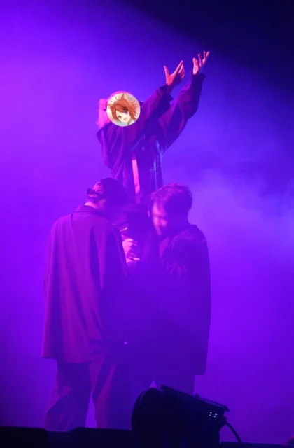 ライブでダンサーに支えられ紫のライトに照らされる莉犬