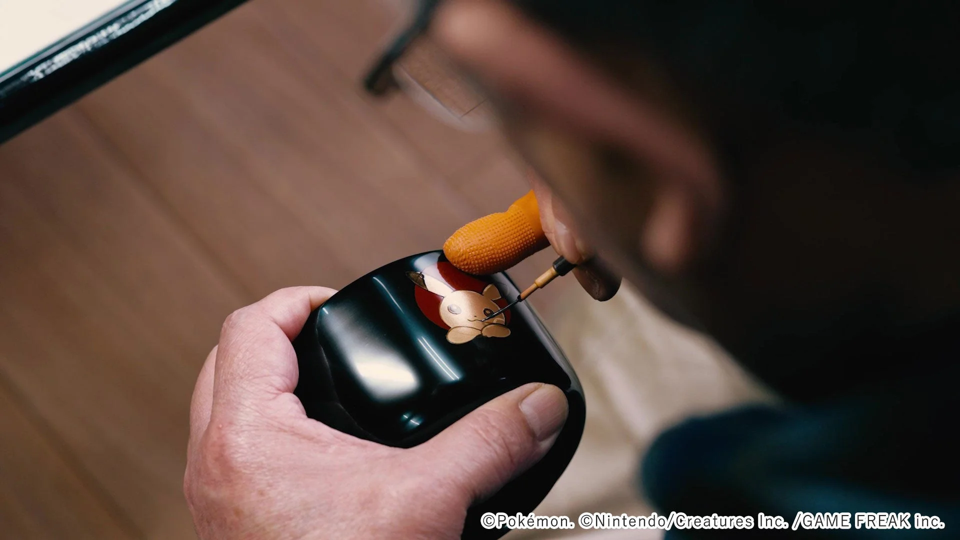 職人が漆器の小椀にウリムーの蒔絵を施す手作業の様子