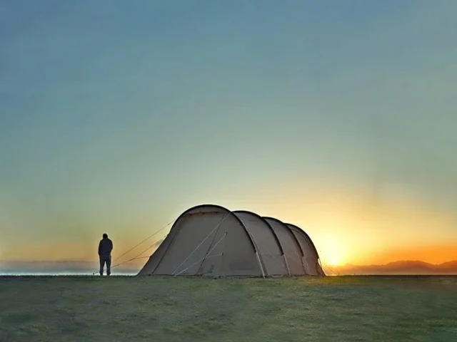夕焼けを背景にDODのテントと人が立つキャンプ風景