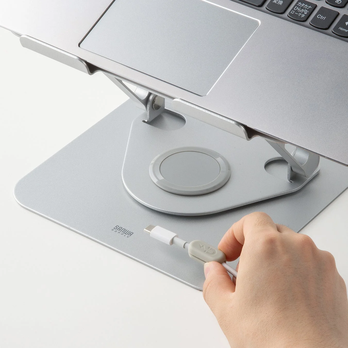 ノートパソコンスタンドの本体にマグネット式のケーブルホルダーを取り付けて整理する様子