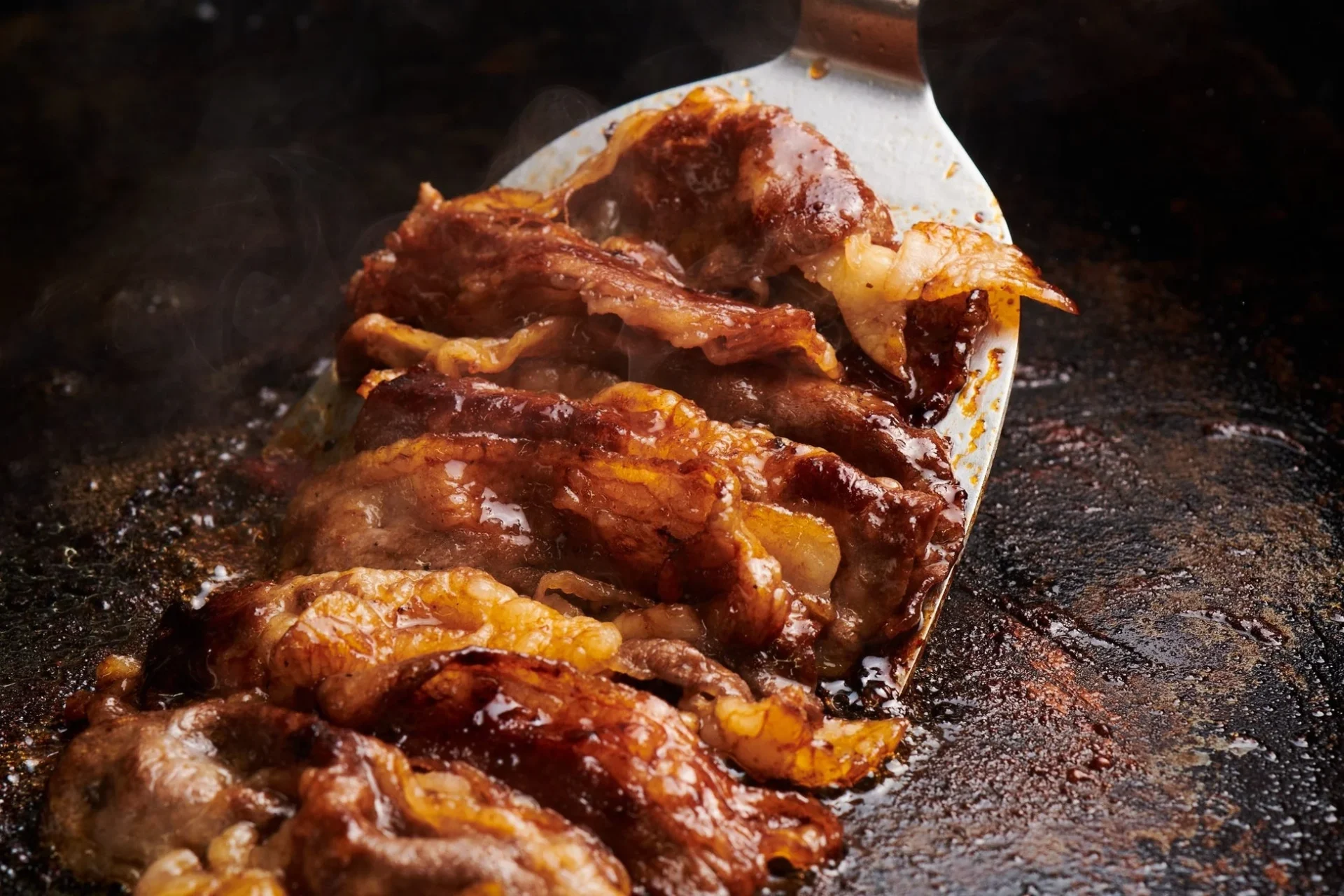 熱々の鉄板で焼かれるジューシーな焼肉のアップ