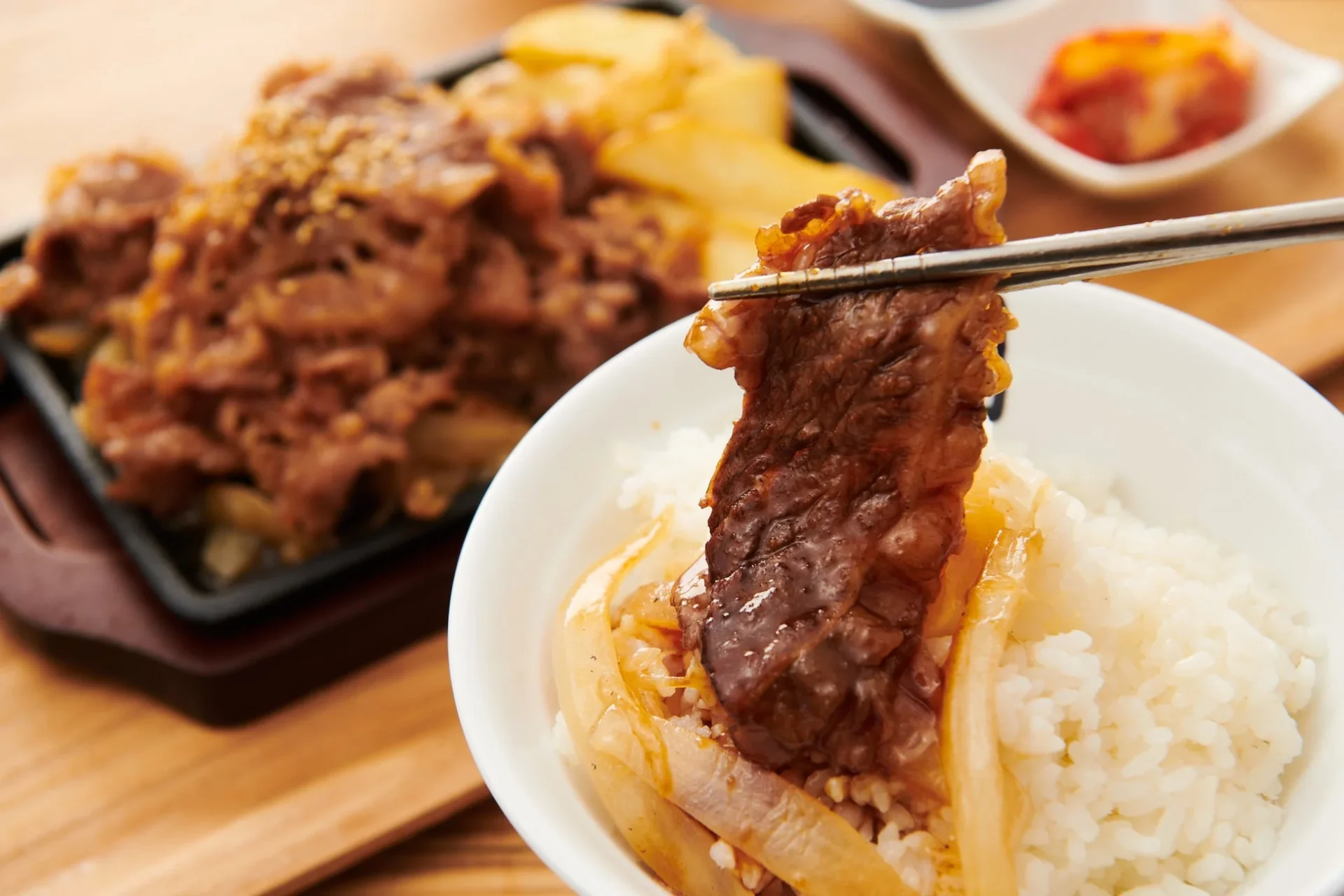 焼肉をご飯に乗せて食べる様子。鉄板焼肉定食のイメージ