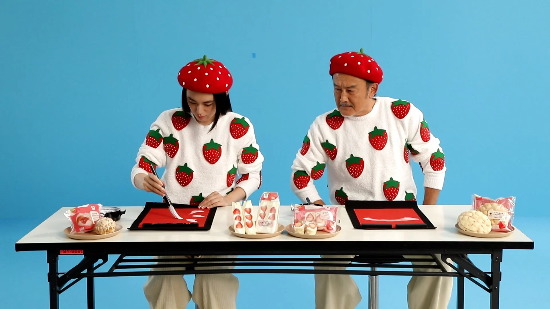 いちごの衣装で書き初めをする吉田鋼太郎さんと八木莉可子さん