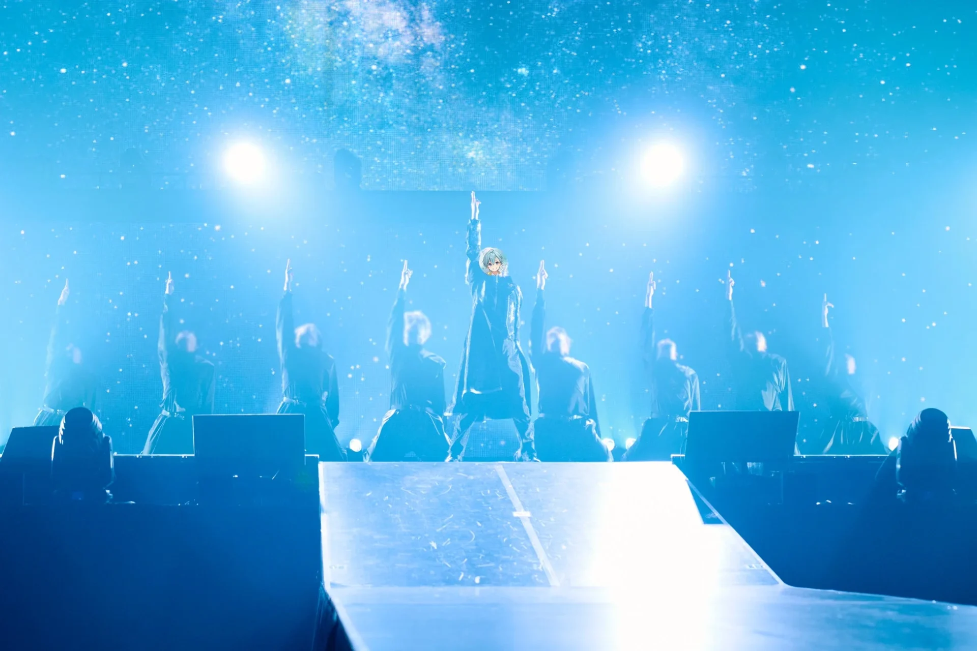 ダンサーと共に青い光の中でパフォーマンスするころん。