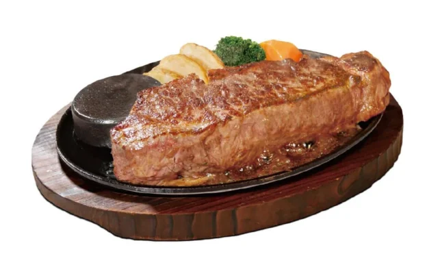 鉄板に乗った焼き立てのサーロインステーキと付け合わせ。