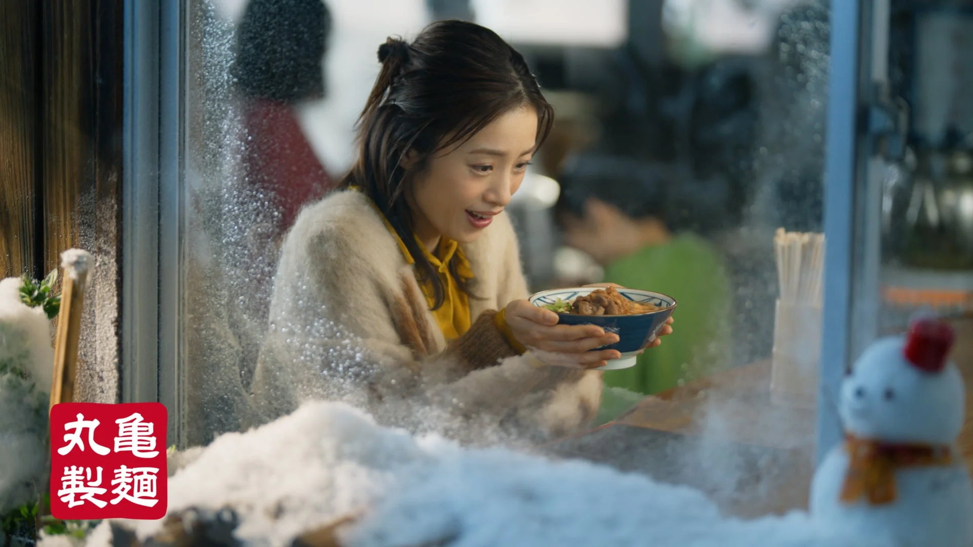 雪が舞う窓辺で温かい肉がさね玉子あんかけうどんを幸せそうに持つ上戸彩さん