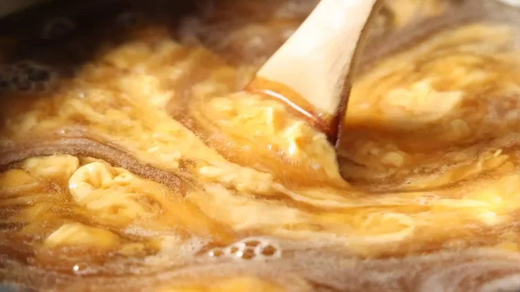 ふわとろ食感を生み出す玉子あんかけを丁寧に混ぜる調理風景