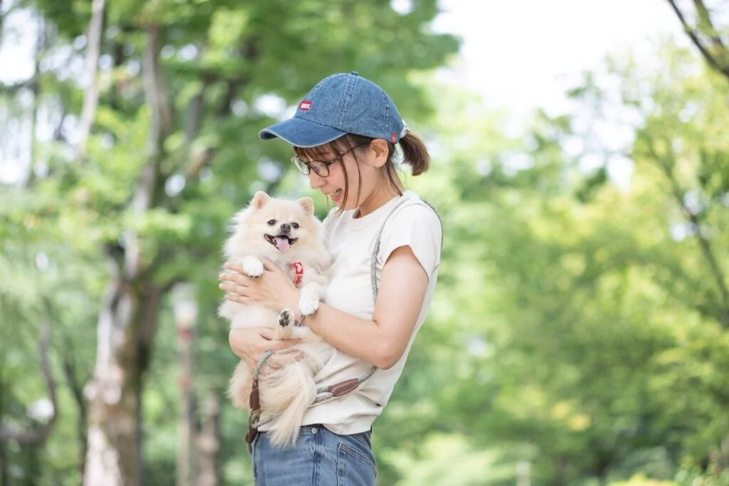 愛犬のポメラニアンを抱き、笑顔を見せる株式会社tent tent代表取締役の小西恵子さん。
