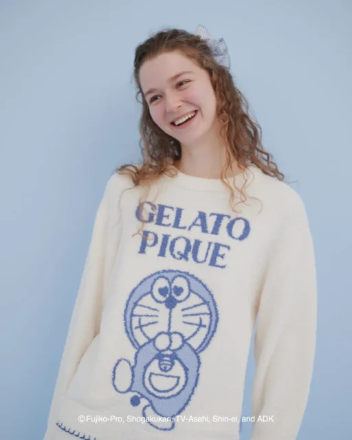 喜の表情のドラえもんニットプルオーバーを着た女性