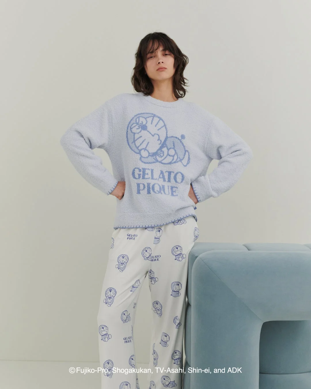 怒の表情のドラえもんニットプルオーバーと総柄パンツを着た女性