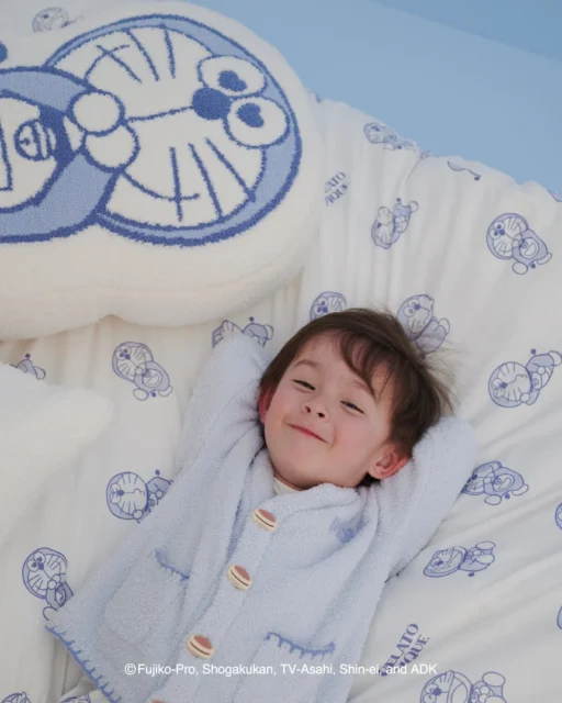 ドラえもんのキッズカーディガンを着て寝具に横たわる子供