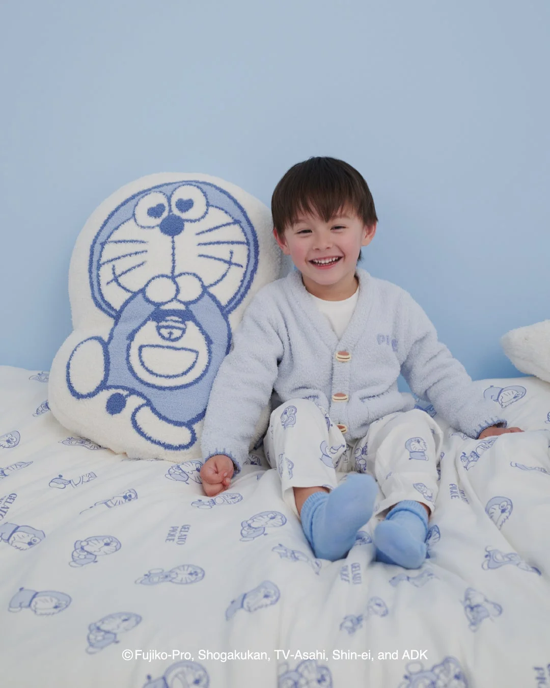 ドラえもんのベビモコジャガードクッションと寝具でくつろぐ子供