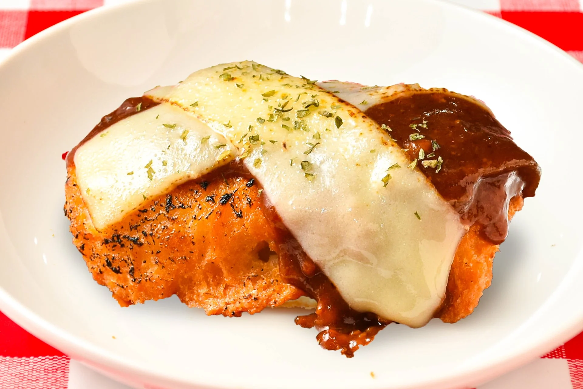 とろーりチーズとデミソースがかかったグラタンコロッケのアップ。