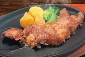 鉄板の上で湯気が立つ牛ジューシーステーキのクローズアップ写真