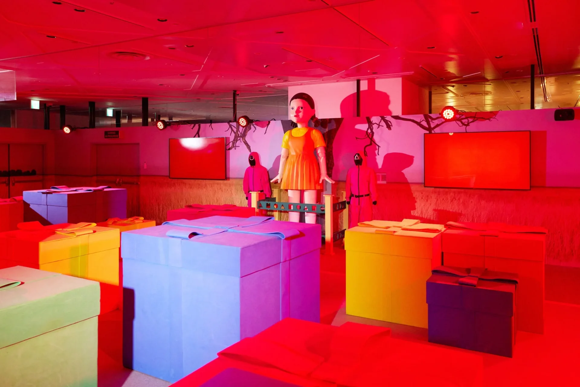 「だるまさんがころんだ」のヨンヒ人形とカラフルなプレゼントボックスが並ぶ会場