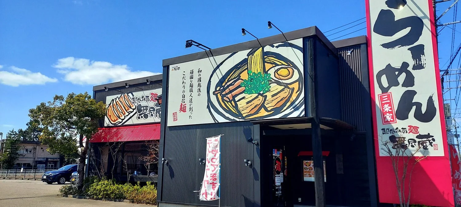 『新潟らーめん 無尽蔵』の外観。大きな看板と店舗の様子がわかる。